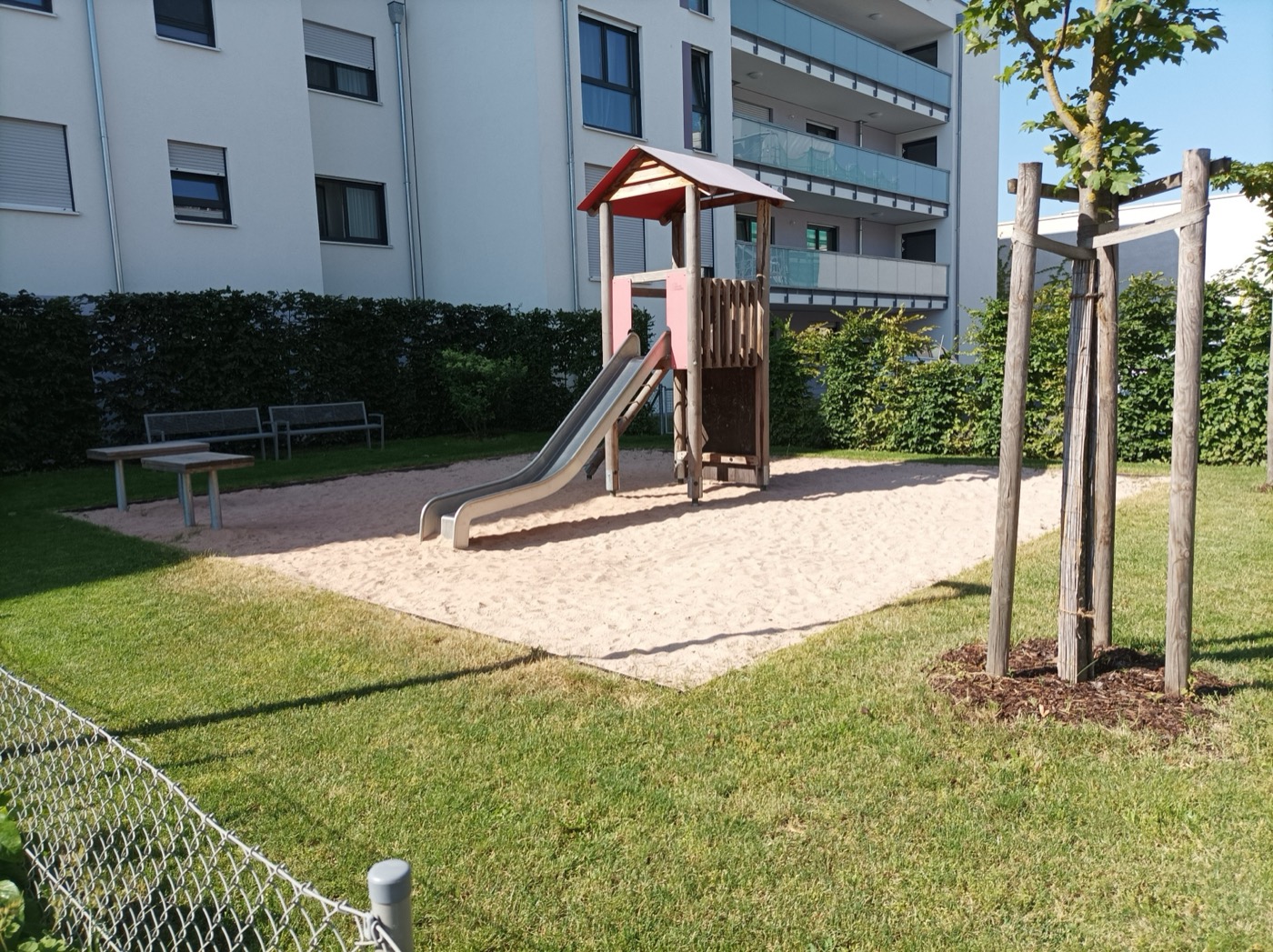 Gepflegte Außenanlage mit Spielplatz und Rasen vor einer Wohnanlage